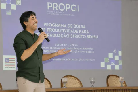 Apresentação da PROPGI com microfone e projeção sobre bolsas de produtividade.